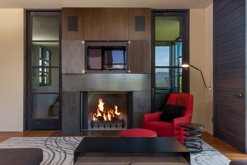 Großes Modernes Wohnzimmer mit verstecktem TV, beiger Wandfarbe, braunem Holzboden, Kamin und Kaminumrandung aus Beton in Boise