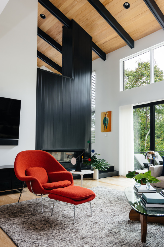 Example of a large mid-century modern open concept light wood floor and brown floor living room design in Nashville with white walls, a two-sided fireplace, a metal fireplace and a wall-mounted tv