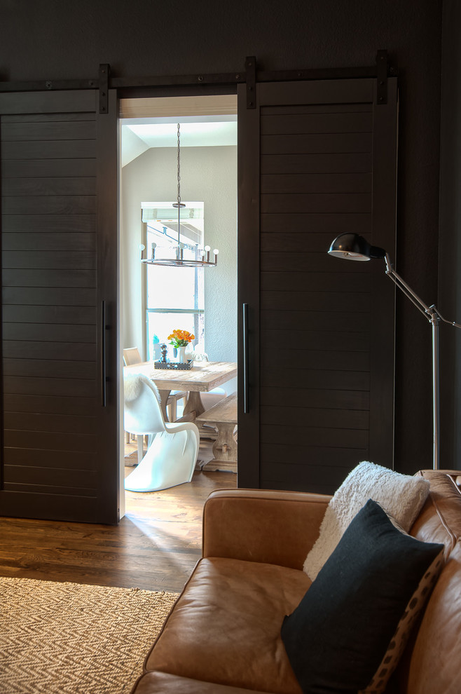 Cette image montre un grand salon rustique fermé avec un mur gris, parquet foncé, une cheminée standard, un manteau de cheminée en pierre, un téléviseur indépendant et un sol marron.