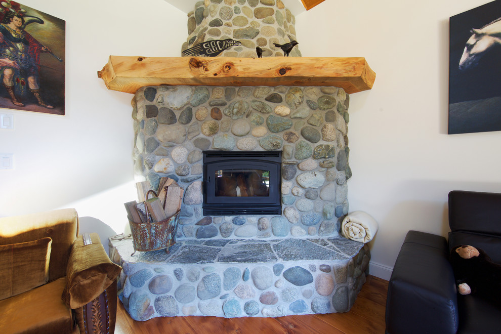 Foto de salón para visitas abierto rural de tamaño medio sin televisor con paredes blancas, suelo de madera en tonos medios, chimenea de esquina y marco de chimenea de piedra