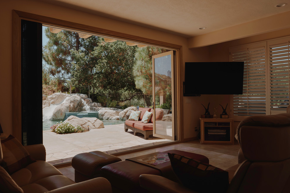 Imagen de salón abierto rústico pequeño sin chimenea con paredes beige, suelo de travertino, televisor colgado en la pared y suelo beige