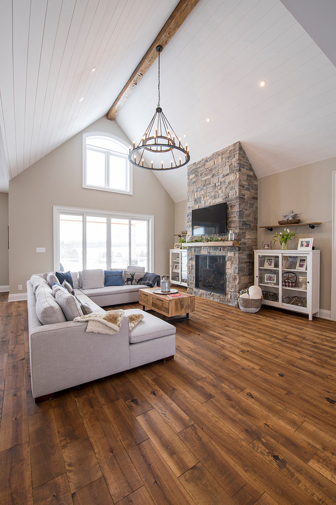Esempio di un soggiorno moderno di medie dimensioni e aperto con pareti beige, pavimento in legno massello medio e TV a parete