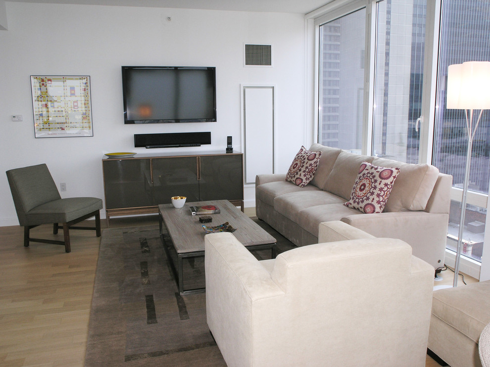 This is an example of a medium sized contemporary open plan living room in New York with white walls, light hardwood flooring, no fireplace and a wall mounted tv.