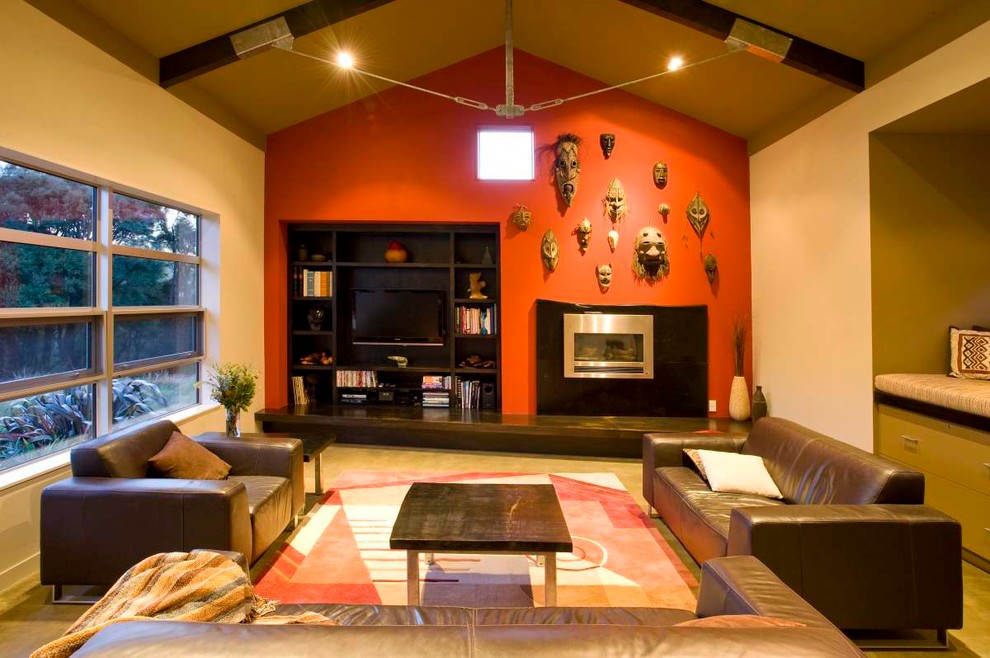 Exempel på ett modernt allrum med öppen planlösning, med röda väggar, betonggolv, en standard öppen spis, en spiselkrans i trä och en inbyggd mediavägg