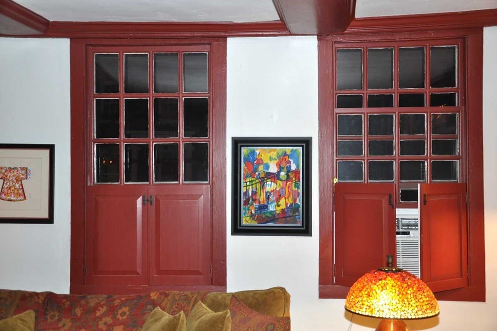 Cette image montre un salon traditionnel avec un mur blanc, un sol en bois brun et un téléviseur encastré.