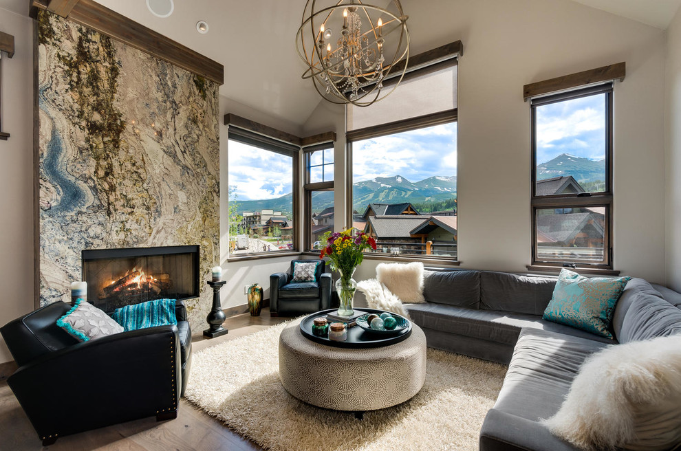 This is an example of a medium sized contemporary open plan living room in Denver with beige walls, dark hardwood flooring, a standard fireplace, a tiled fireplace surround and brown floors.