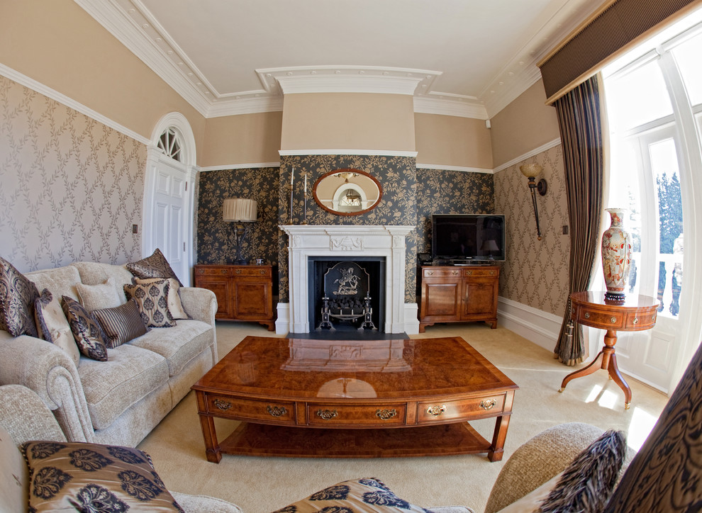 Cette image montre un salon traditionnel de taille moyenne avec un mur beige, moquette, une cheminée standard, un manteau de cheminée en pierre, un téléviseur indépendant et un sol beige.