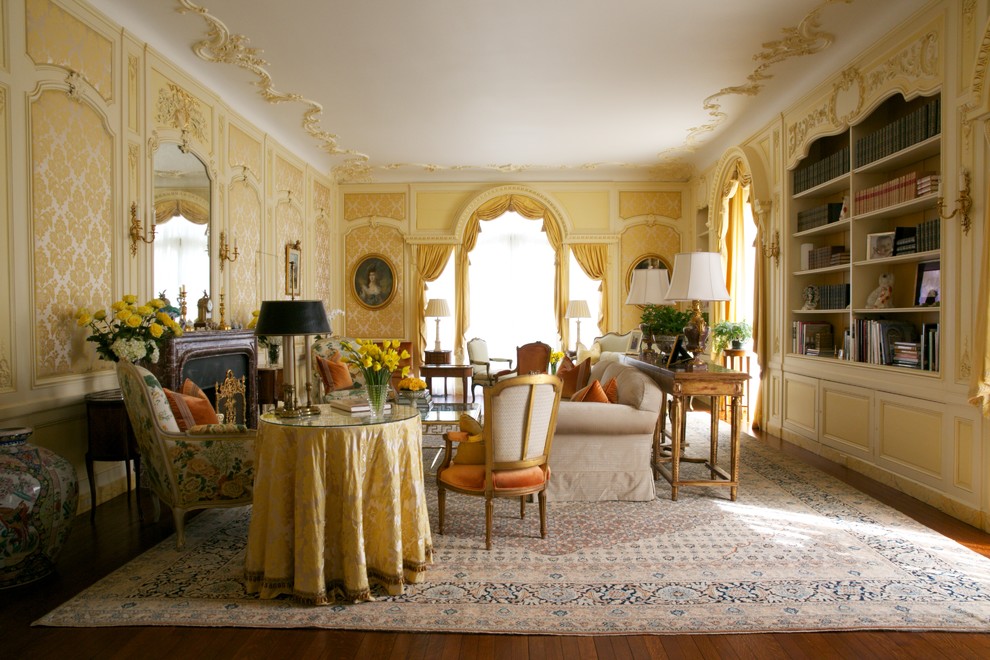 На фото: огромная изолированная гостиная комната в классическом стиле с желтыми стенами, паркетным полом среднего тона, стандартным камином и фасадом камина из камня