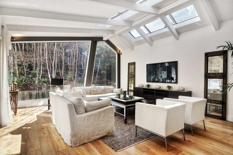 Esempio di un soggiorno design con pareti bianche, pavimento in legno massello medio, nessun camino e TV a parete