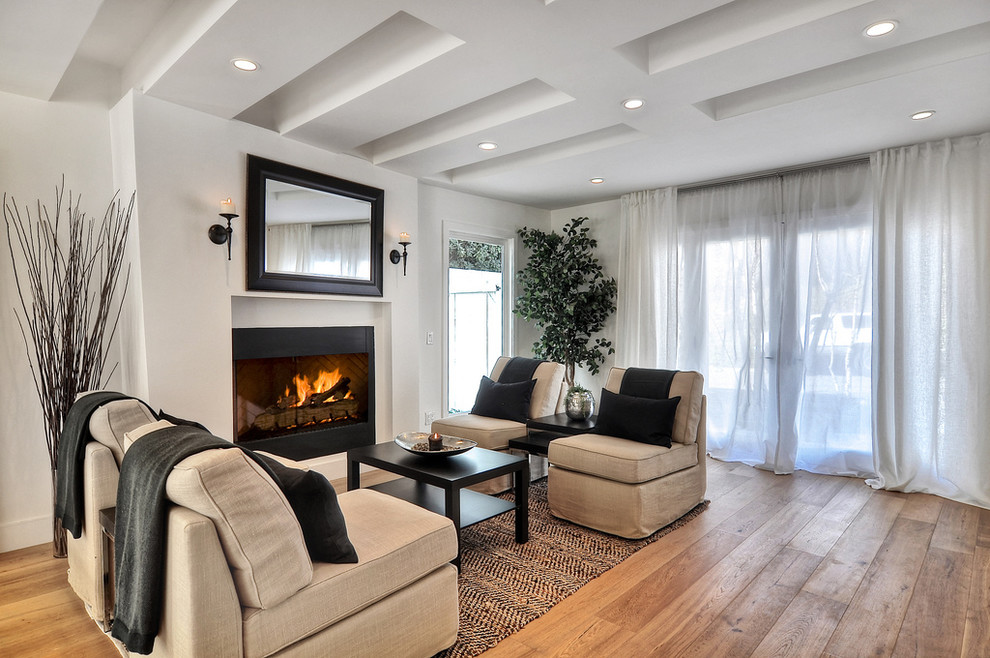 Ejemplo de salón actual sin televisor con paredes blancas, suelo de madera en tonos medios y todas las chimeneas