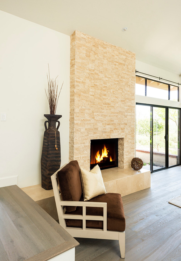 Photo of a large modern open plan living room in Orange County with white walls, medium hardwood flooring, a two-sided fireplace, a tiled fireplace surround and beige floors.