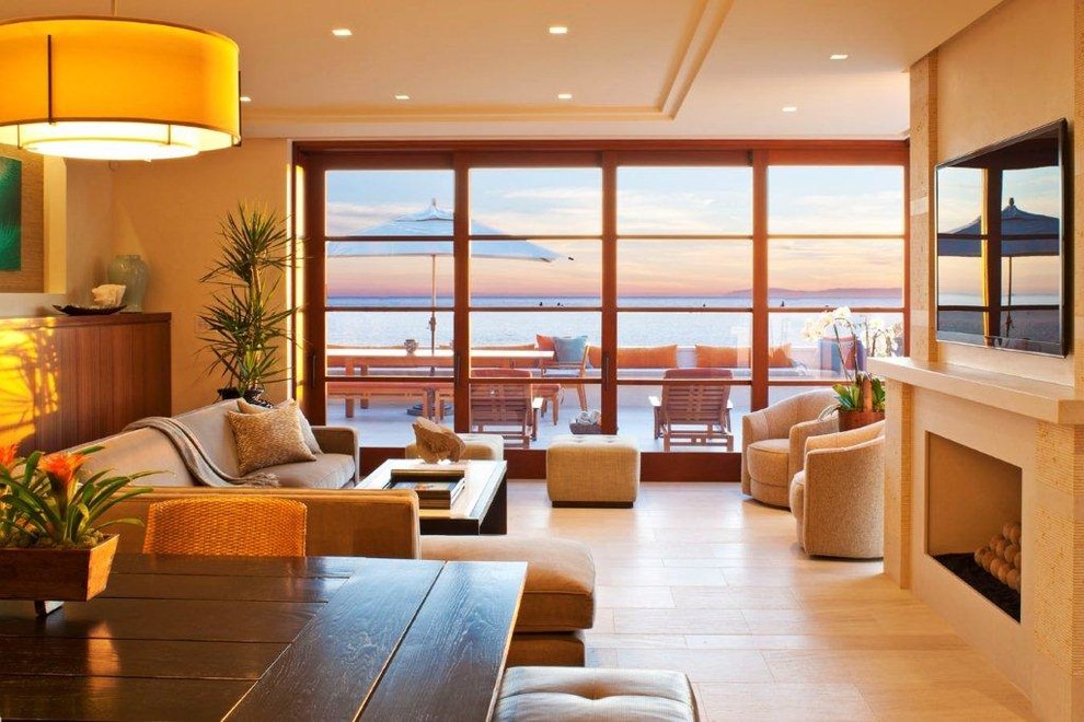 Идея дизайна: гостиная комната среднего размера в морском стиле с бежевыми стенами, полом из керамогранита, стандартным камином, фасадом камина из плитки, телевизором на стене и бежевым полом