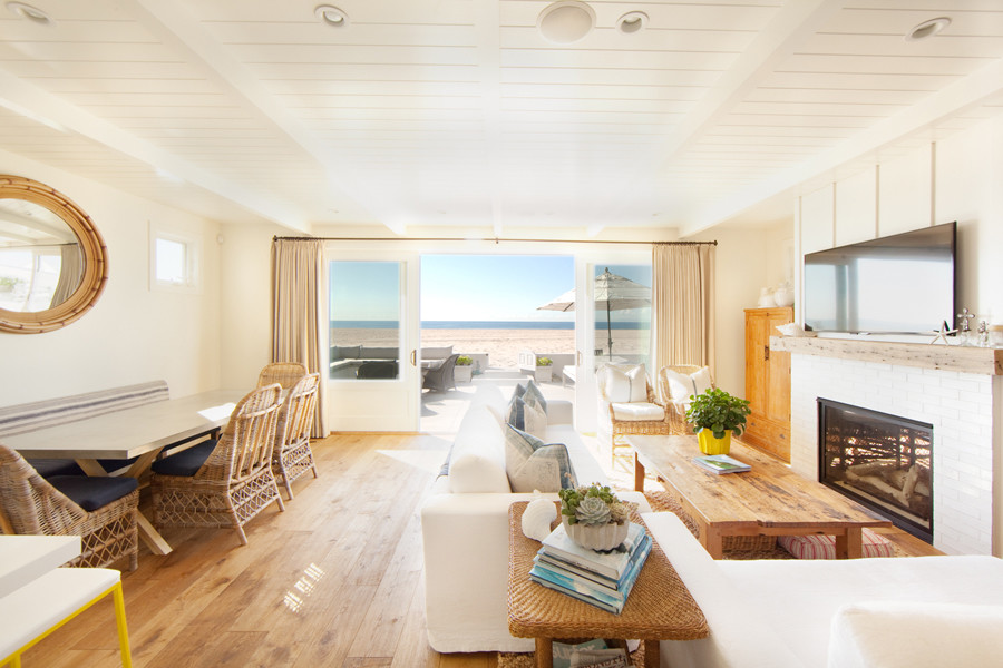 Cette photo montre un grand salon bord de mer ouvert avec un mur blanc, parquet clair, une cheminée standard, un manteau de cheminée en carrelage et un téléviseur fixé au mur.