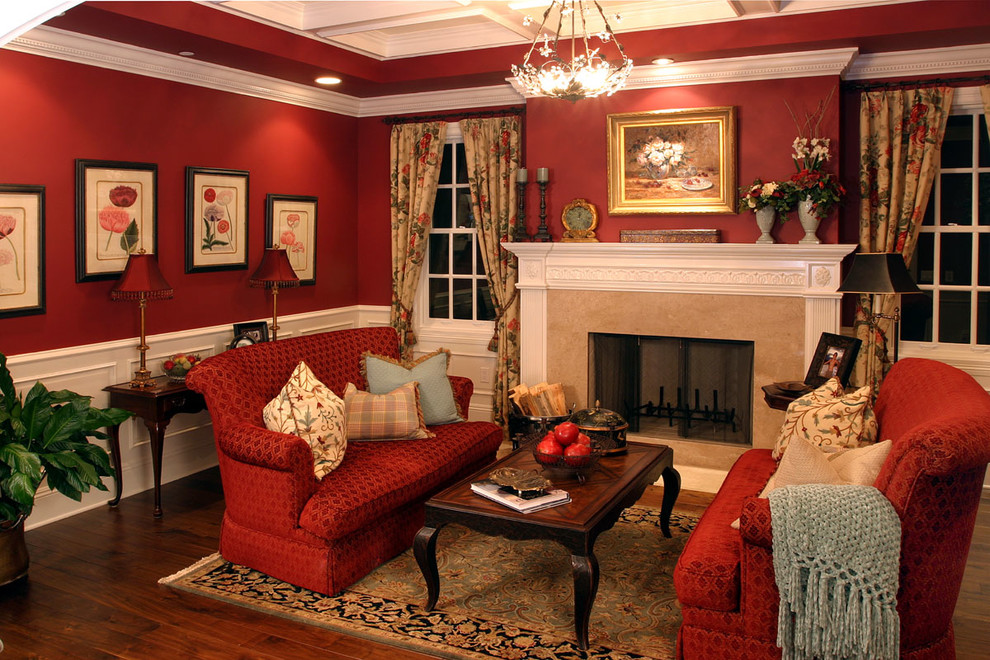 На фото: большая парадная, изолированная гостиная комната в классическом стиле с красными стенами, темным паркетным полом и фасадом камина из камня