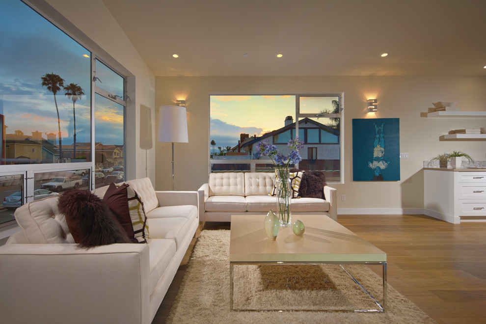 This is an example of a small contemporary open plan living room in Orange County with white walls and light hardwood flooring.