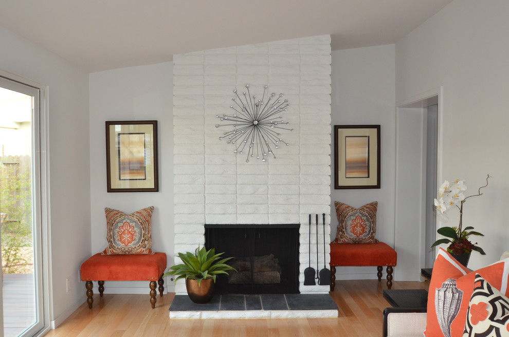 Inspiration for a small contemporary formal enclosed living room in Orange County with white walls, light hardwood flooring, a standard fireplace, a brick fireplace surround and no tv.