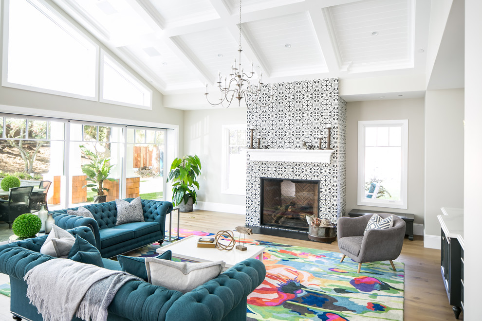 Offenes Klassisches Wohnzimmer mit grauer Wandfarbe, braunem Holzboden, Kamin, gefliester Kaminumrandung und braunem Boden in Orange County