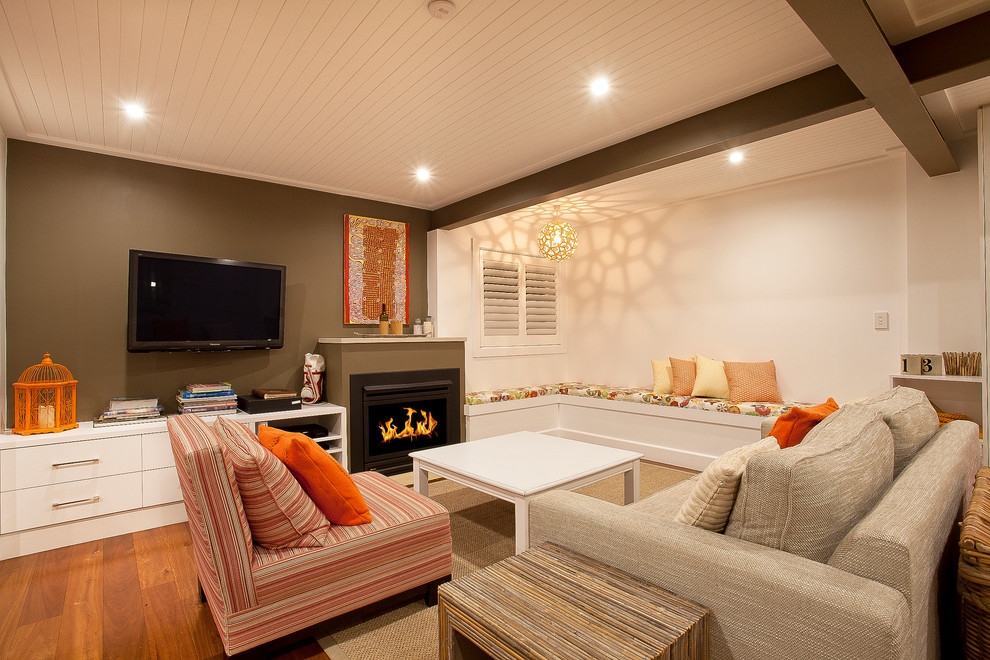 На фото: гостиная комната в стиле неоклассика (современная классика) с коричневыми стенами, темным паркетным полом, стандартным камином и телевизором на стене с