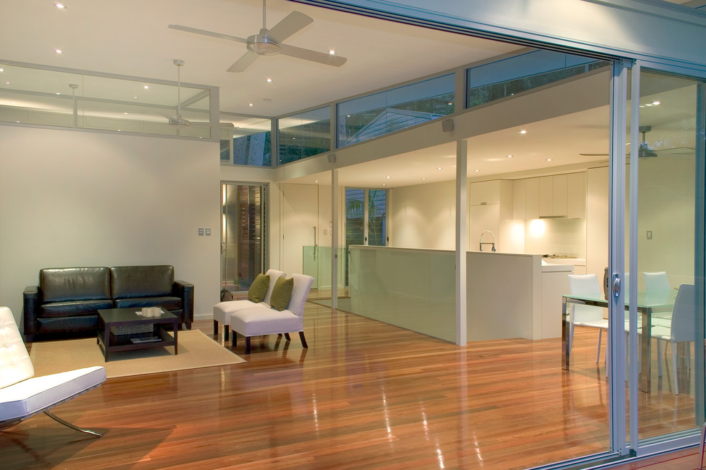 This is an example of a contemporary open plan living room in Sydney with white walls and medium hardwood flooring.