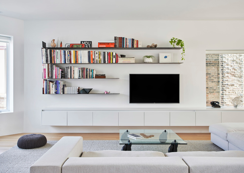 Modern open plan living room in Chicago with no fireplace, a wall mounted tv, brown floors, white walls and medium hardwood flooring.