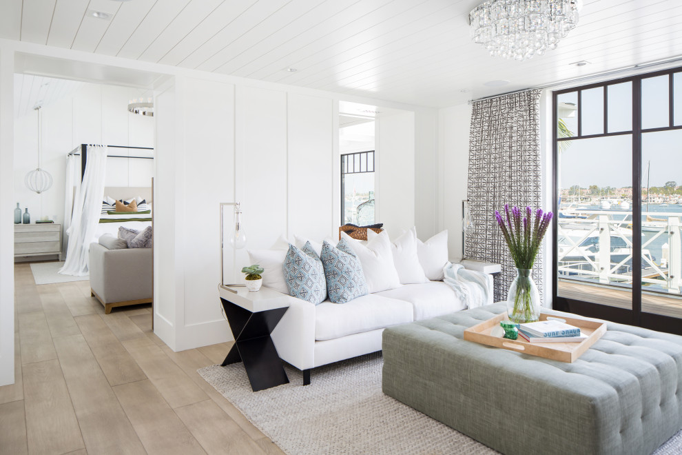 Стильный дизайн: огромная изолированная гостиная комната в морском стиле с белыми стенами, светлым паркетным полом, стандартным камином, фасадом камина из плитки, телевизором на стене и бежевым полом - последний тренд