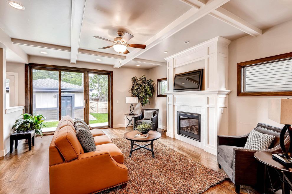 Photo of a traditional formal open plan living room in Denver with beige walls, dark hardwood flooring, a standard fireplace and a freestanding tv.