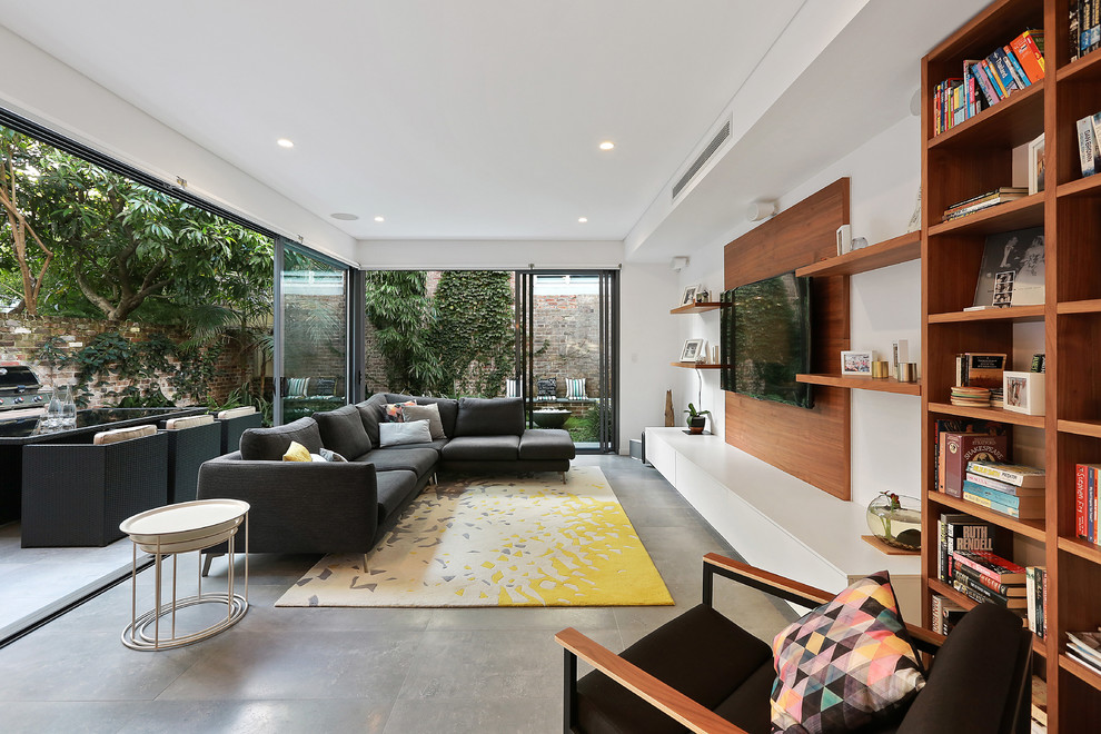 Идея дизайна: изолированная гостиная комната в современном стиле с коричневыми стенами, бетонным полом, телевизором на стене и серым полом без камина