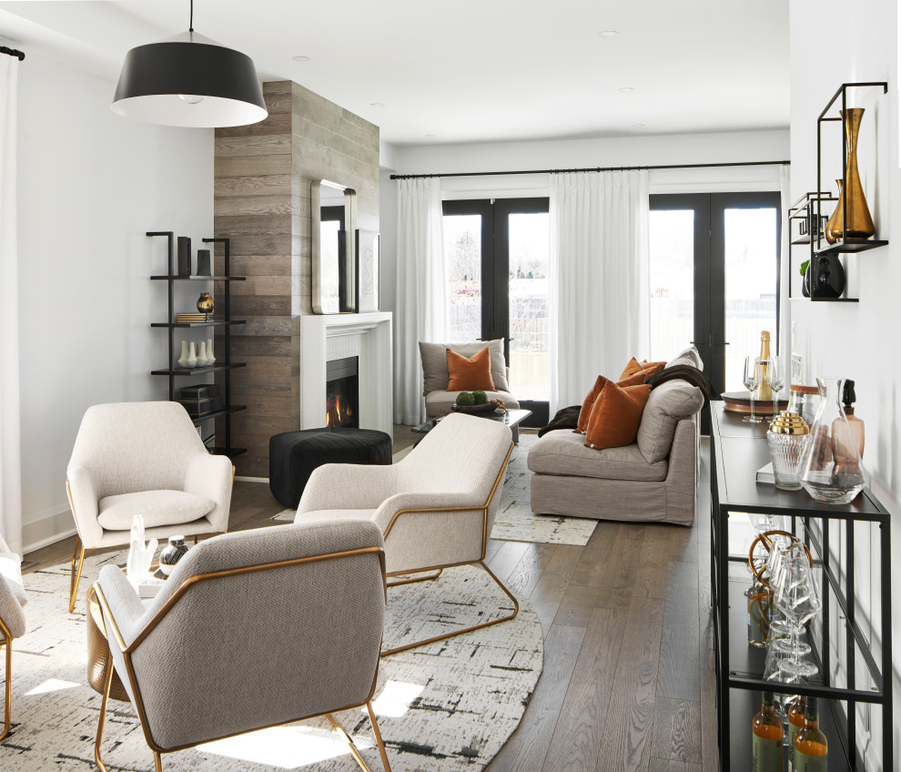 This is an example of a large modern open plan living room in Toronto with a home bar, white walls, medium hardwood flooring, a standard fireplace, a wooden fireplace surround, no tv and grey floors.