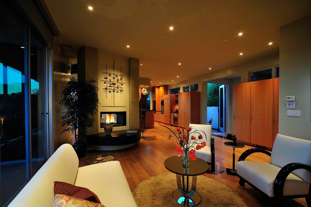 Ispirazione per un soggiorno minimalista con pavimento in legno massello medio e camino bifacciale
