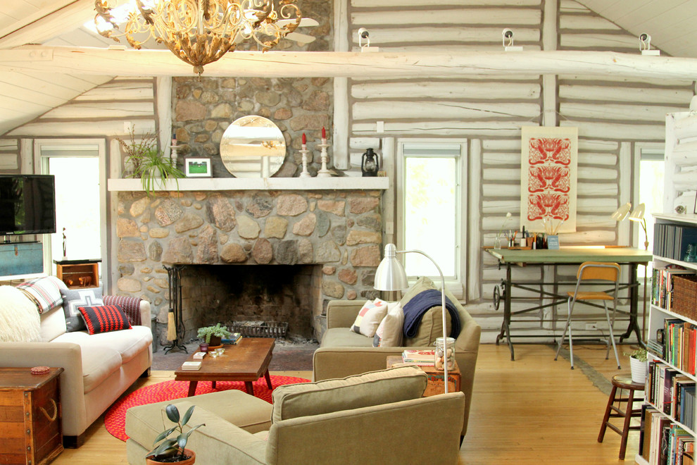 Cette photo montre un salon montagne avec un sol en bois brun, une cheminée standard et un manteau de cheminée en pierre.