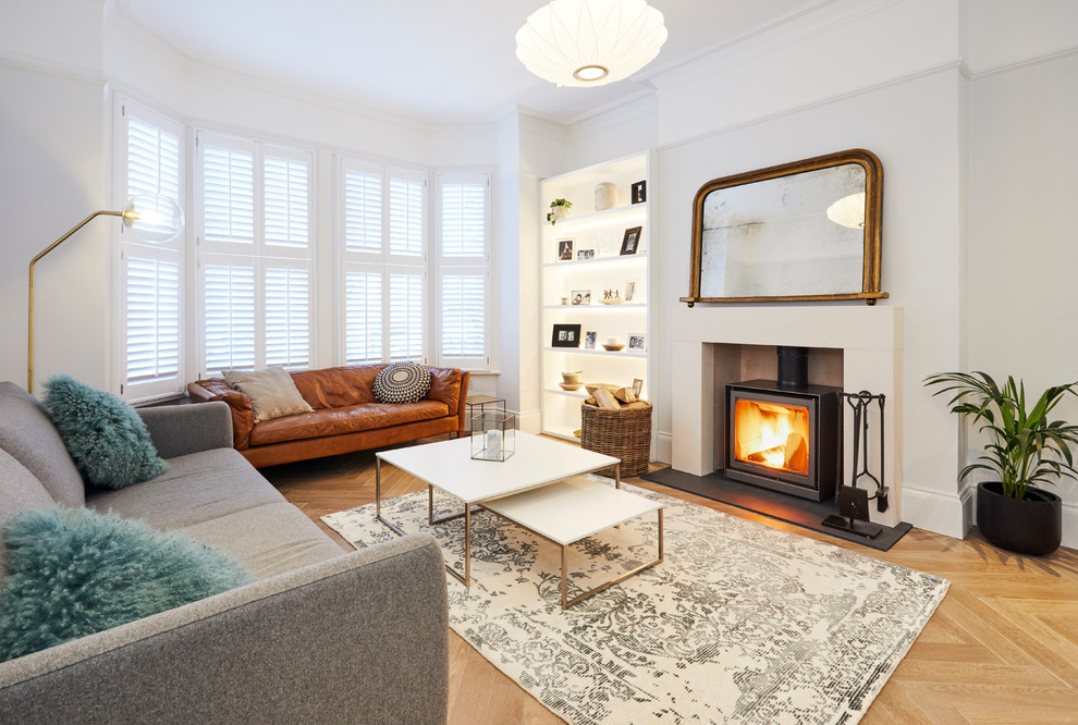 Mittelgroßes Modernes Wohnzimmer mit grauer Wandfarbe, Kaminofen, verputzter Kaminumrandung, beigem Boden und braunem Holzboden in London