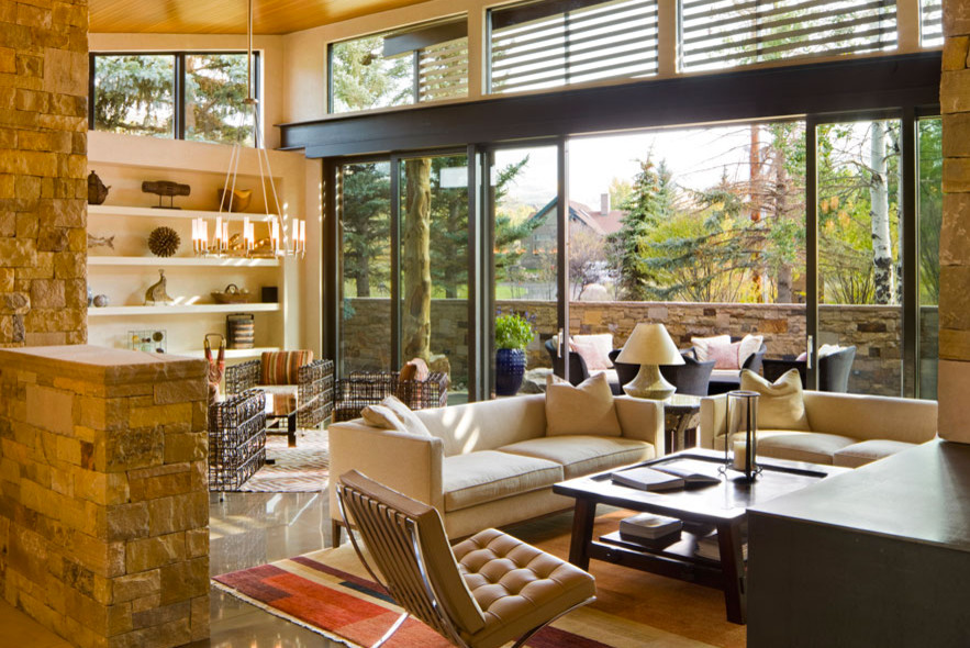 Example of a large trendy open concept medium tone wood floor living room design in Denver with beige walls, a two-sided fireplace, a stone fireplace and a wall-mounted tv