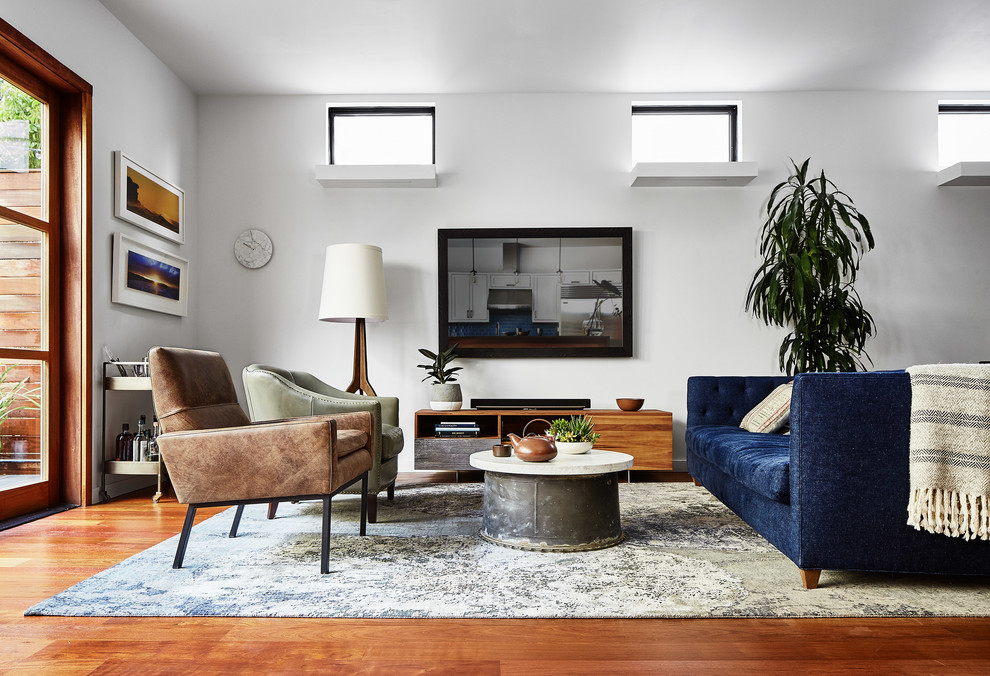 Esempio di un grande soggiorno moderno aperto con pareti bianche, pavimento in legno massello medio, nessun camino, TV a parete e pavimento marrone
