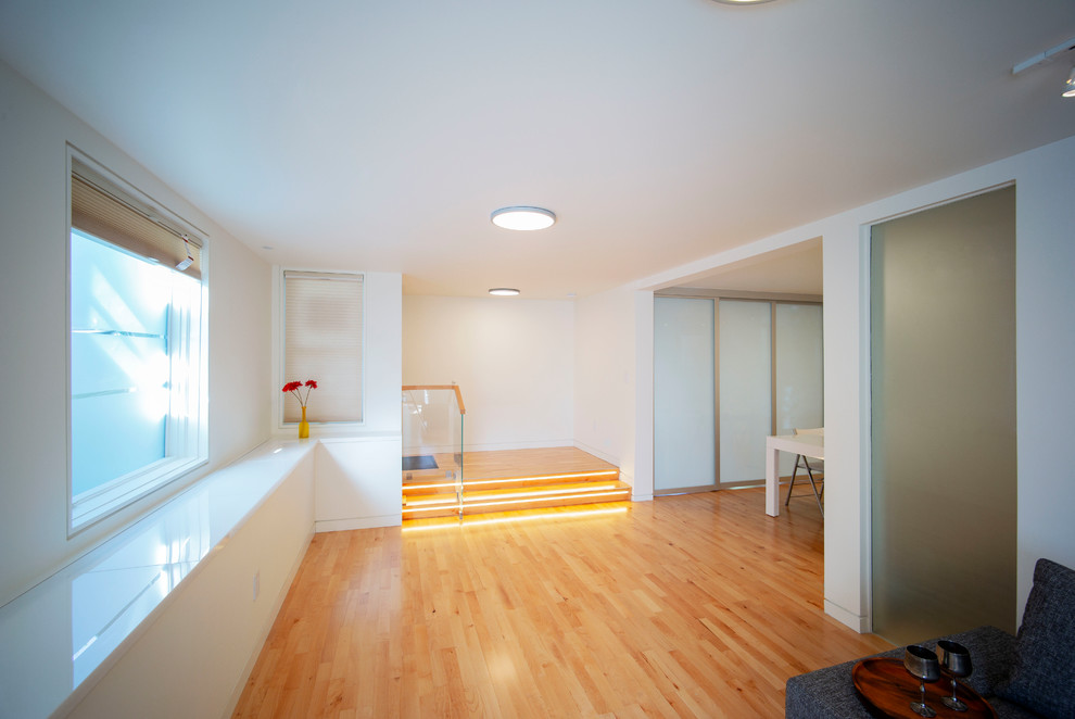 Cette photo montre un petit salon tendance ouvert avec un mur blanc, un sol en bois brun, un téléviseur fixé au mur et un sol marron.