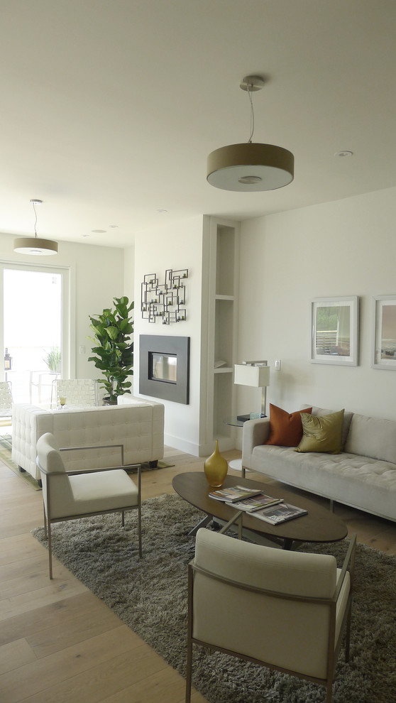 Esempio di un piccolo soggiorno design chiuso con parquet chiaro e camino classico