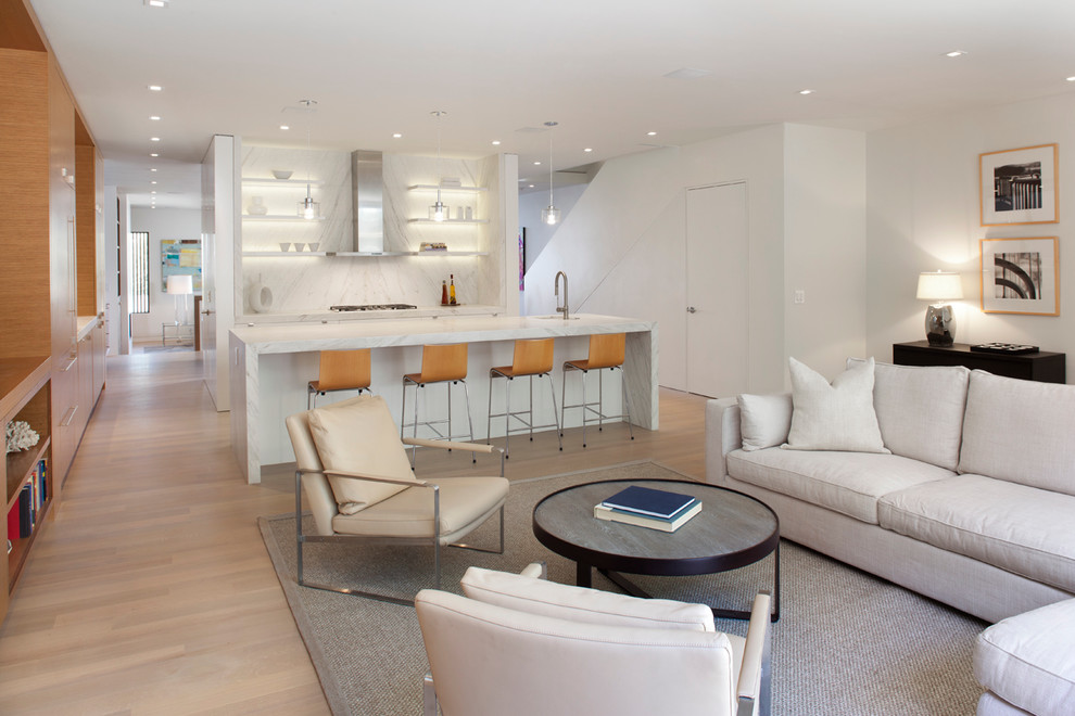 Aménagement d'un salon moderne ouvert avec un mur blanc, parquet clair et un sol beige.
