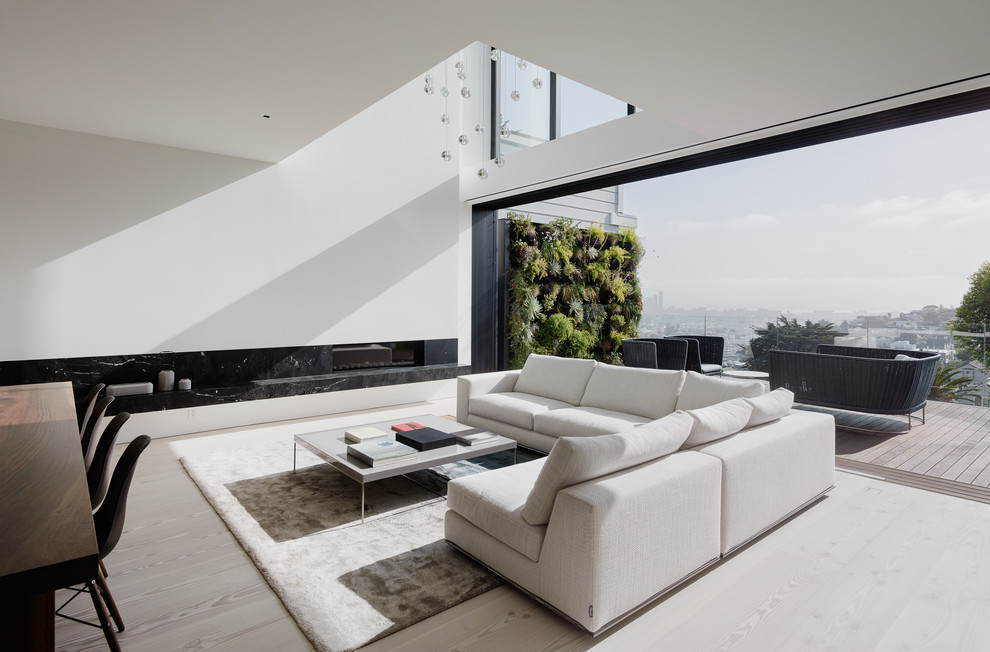 This is an example of a modern living room in San Francisco with white walls, light hardwood flooring, a ribbon fireplace, no tv and grey floors.