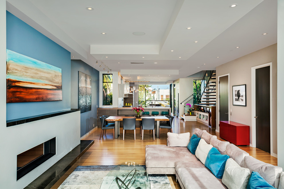 Идея дизайна: открытая гостиная комната среднего размера в современном стиле с светлым паркетным полом, горизонтальным камином и фасадом камина из штукатурки без телевизора