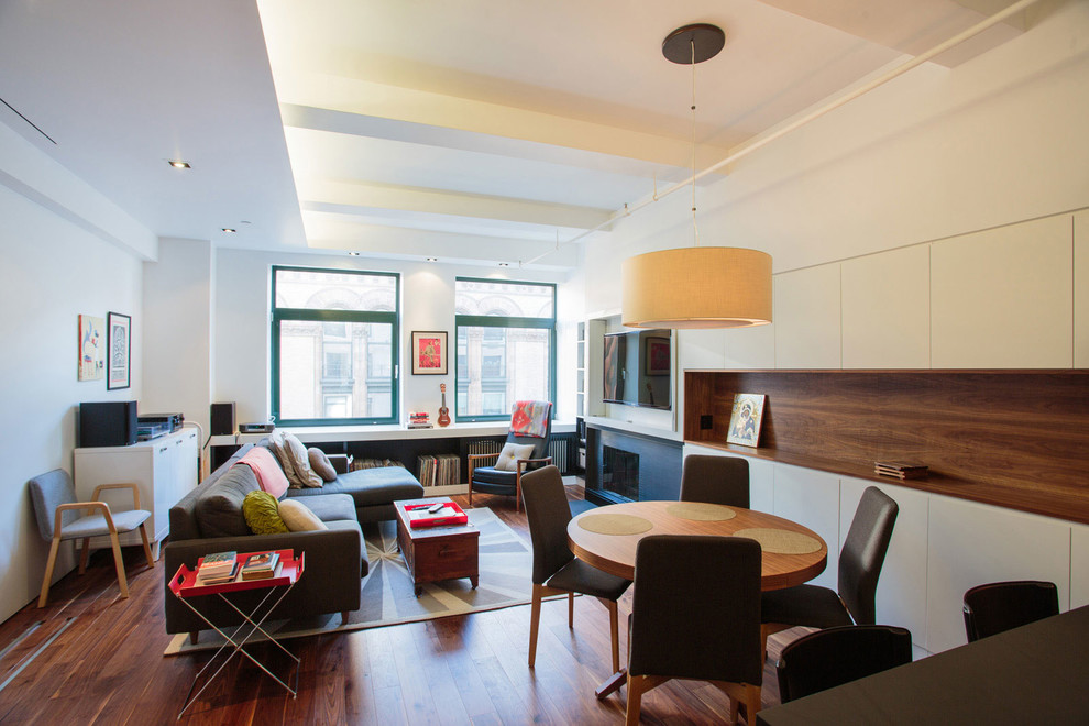 Kleines, Offenes Modernes Wohnzimmer mit Kamin, TV-Wand, braunem Holzboden, Kaminumrandung aus Metall, weißer Wandfarbe und braunem Boden in New York