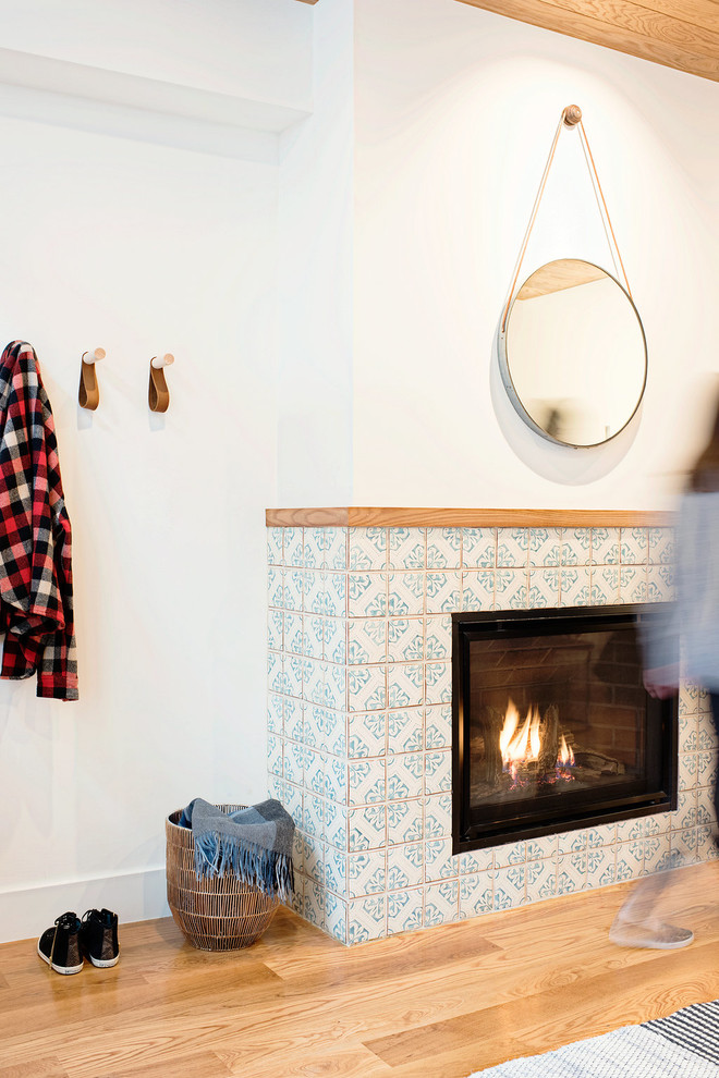 サンフランシスコにある小さな北欧スタイルのおしゃれなリビング (白い壁、淡色無垢フローリング、標準型暖炉、タイルの暖炉まわり、テレビなし) の写真