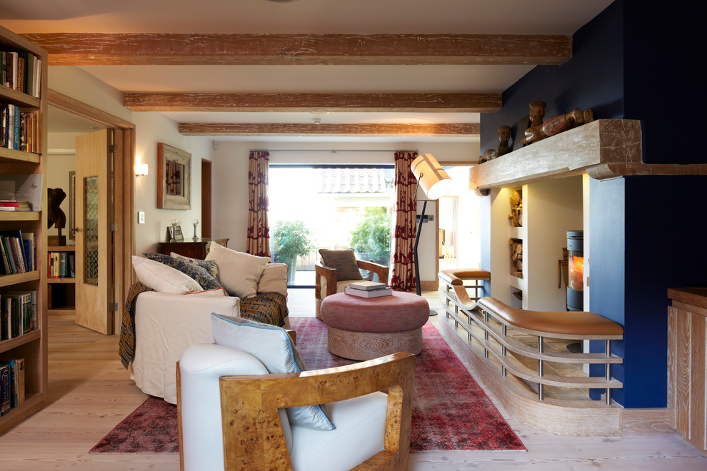 Стильный дизайн: изолированная гостиная комната среднего размера в морском стиле с с книжными шкафами и полками, синими стенами, светлым паркетным полом, печью-буржуйкой, фасадом камина из дерева и скрытым телевизором - последний тренд