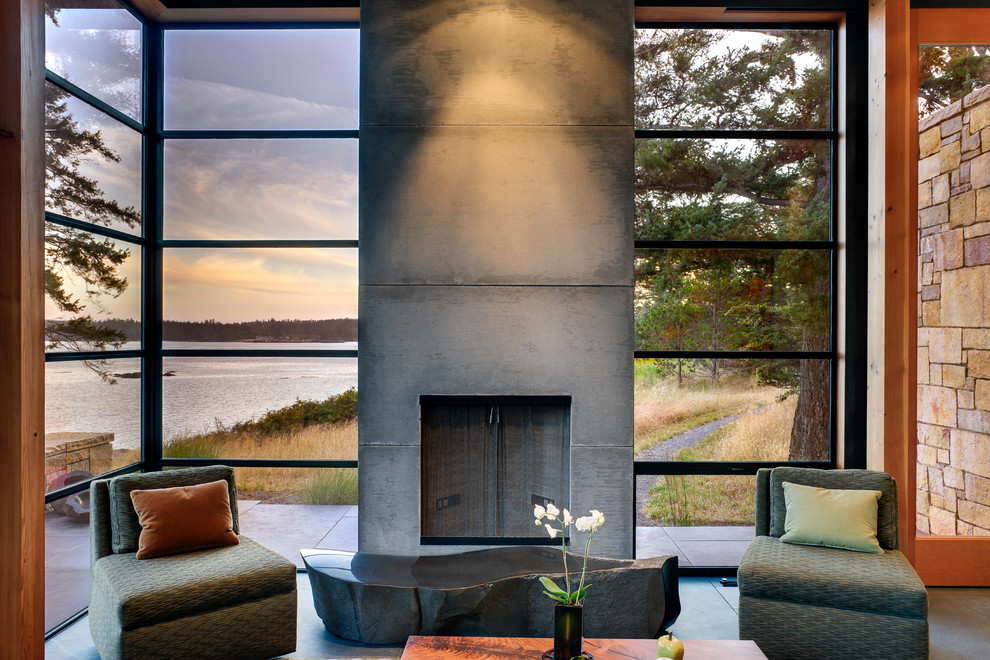 Ejemplo de salón abierto moderno de tamaño medio con marco de chimenea de hormigón, paredes grises, suelo de pizarra y todas las chimeneas
