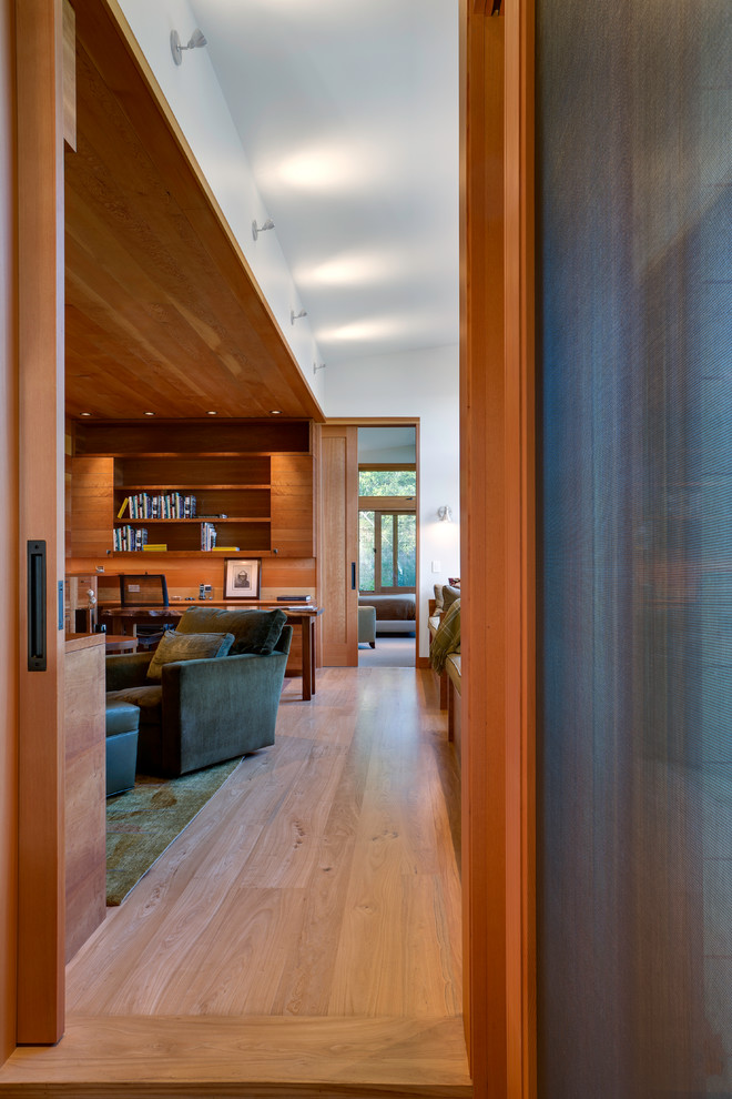 Foto de biblioteca en casa abierta moderna de tamaño medio con paredes blancas y suelo de madera en tonos medios