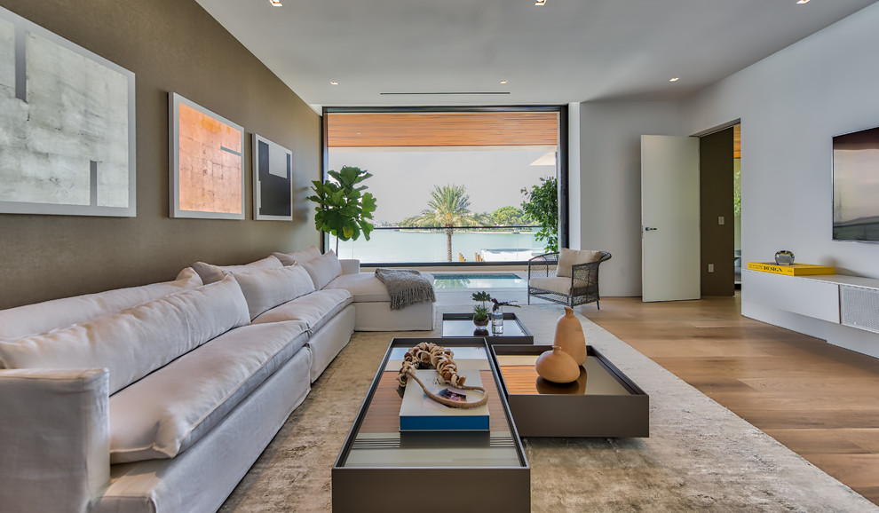 Modernes Wohnzimmer mit weißer Wandfarbe, hellem Holzboden, TV-Wand und braunem Boden in Miami