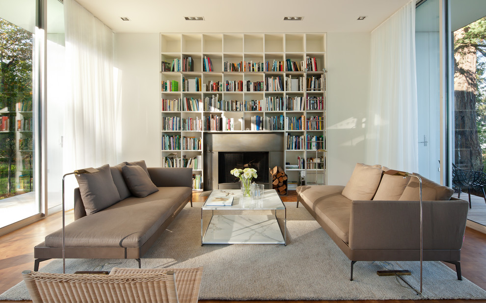 Diseño de biblioteca en casa abierta minimalista de tamaño medio con todas las chimeneas, paredes blancas y marco de chimenea de hormigón