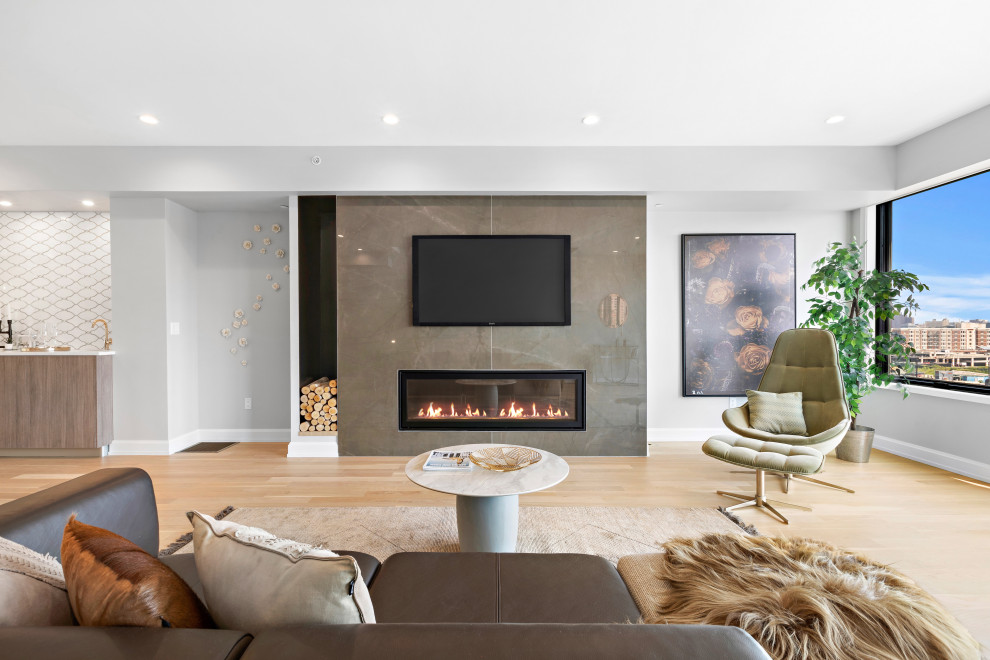 Contemporary open plan living room in New York with grey walls, light hardwood flooring, a ribbon fireplace, a wall mounted tv and beige floors.