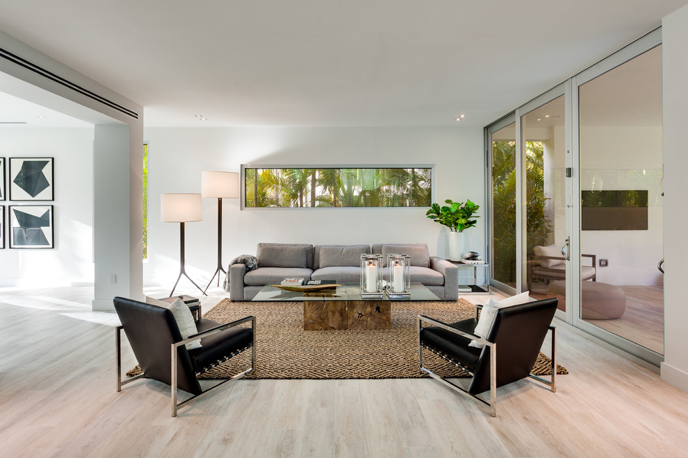 Contemporary living room in Miami with white walls, beige floors and feature lighting.