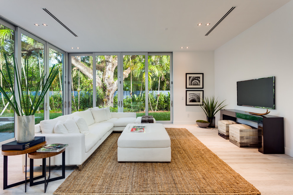 Стильный дизайн: гостиная комната в современном стиле с белыми стенами, телевизором на стене и бежевым полом - последний тренд