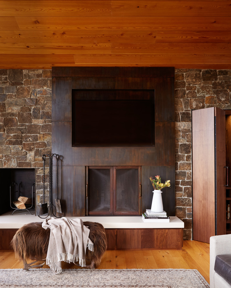Идея дизайна: гостиная комната в стиле рустика с стандартным камином, фасадом камина из дерева и телевизором на стене