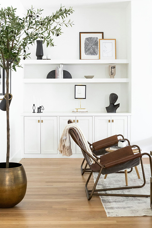 Inspiration pour un grand salon minimaliste ouvert avec un mur blanc, parquet clair, cheminée suspendue, un manteau de cheminée en plâtre, un téléviseur fixé au mur et un sol marron.
